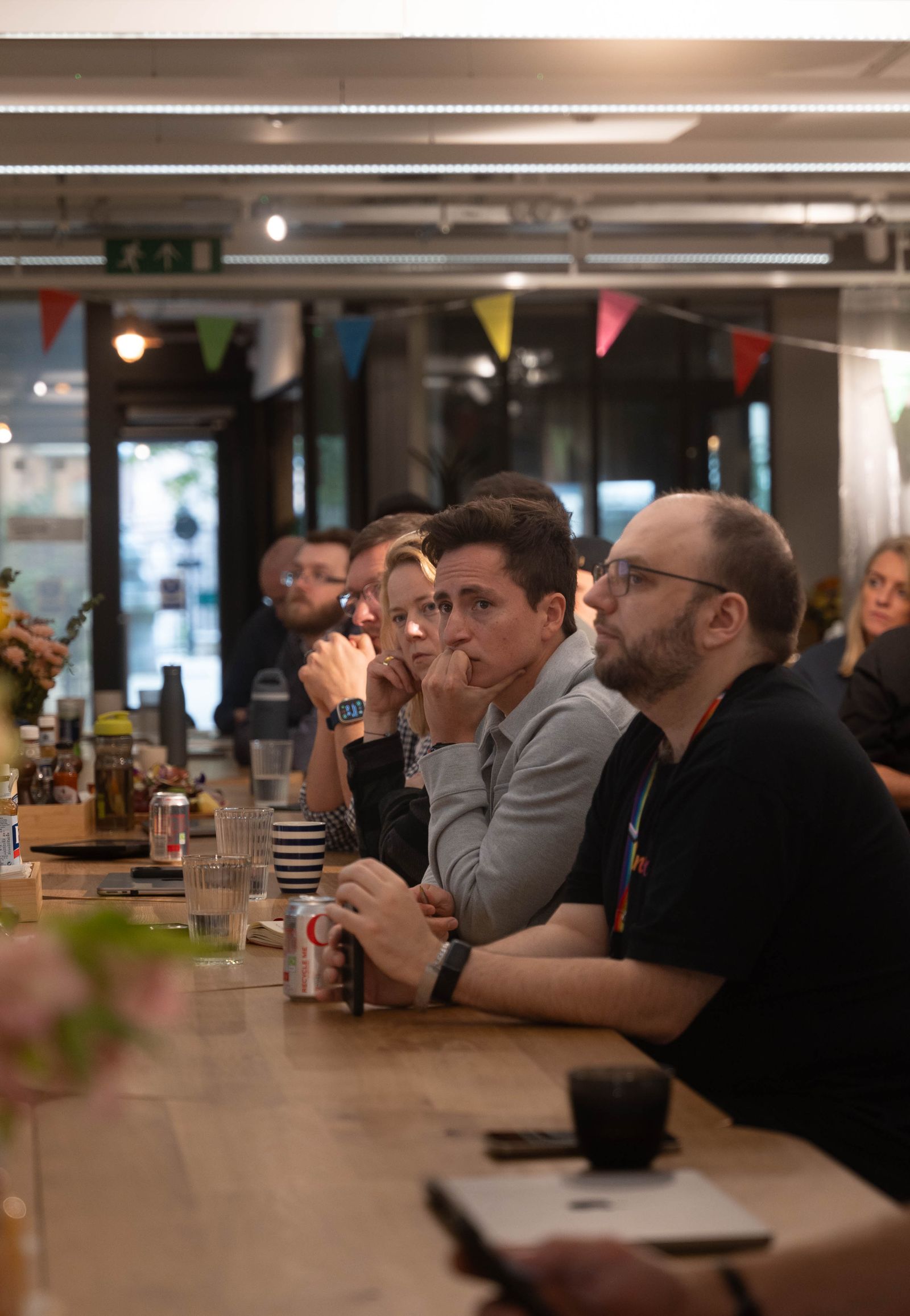 A diverse team quietly listening during a workplace meeting around a wooden table.