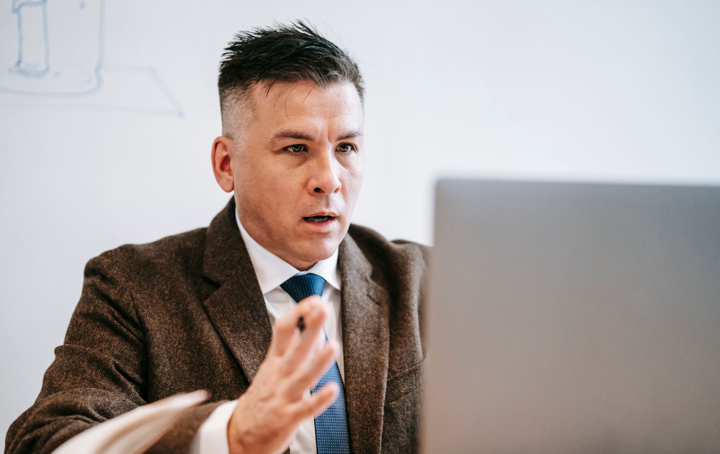 Adult in mid-conversation on a laptop video call, focused and engaged
