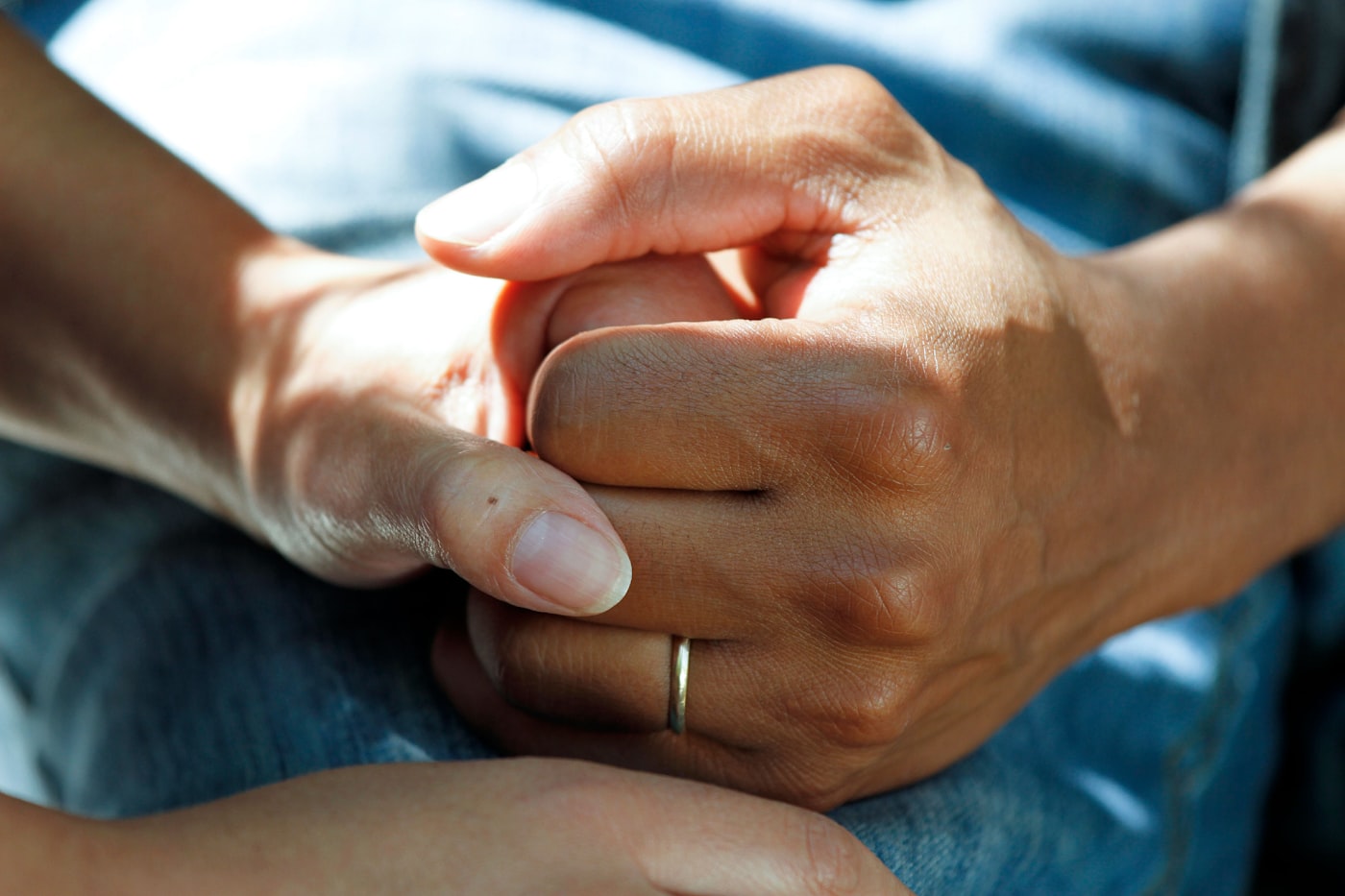 Two hands gently clasped together in a quiet, dignified moment of support.