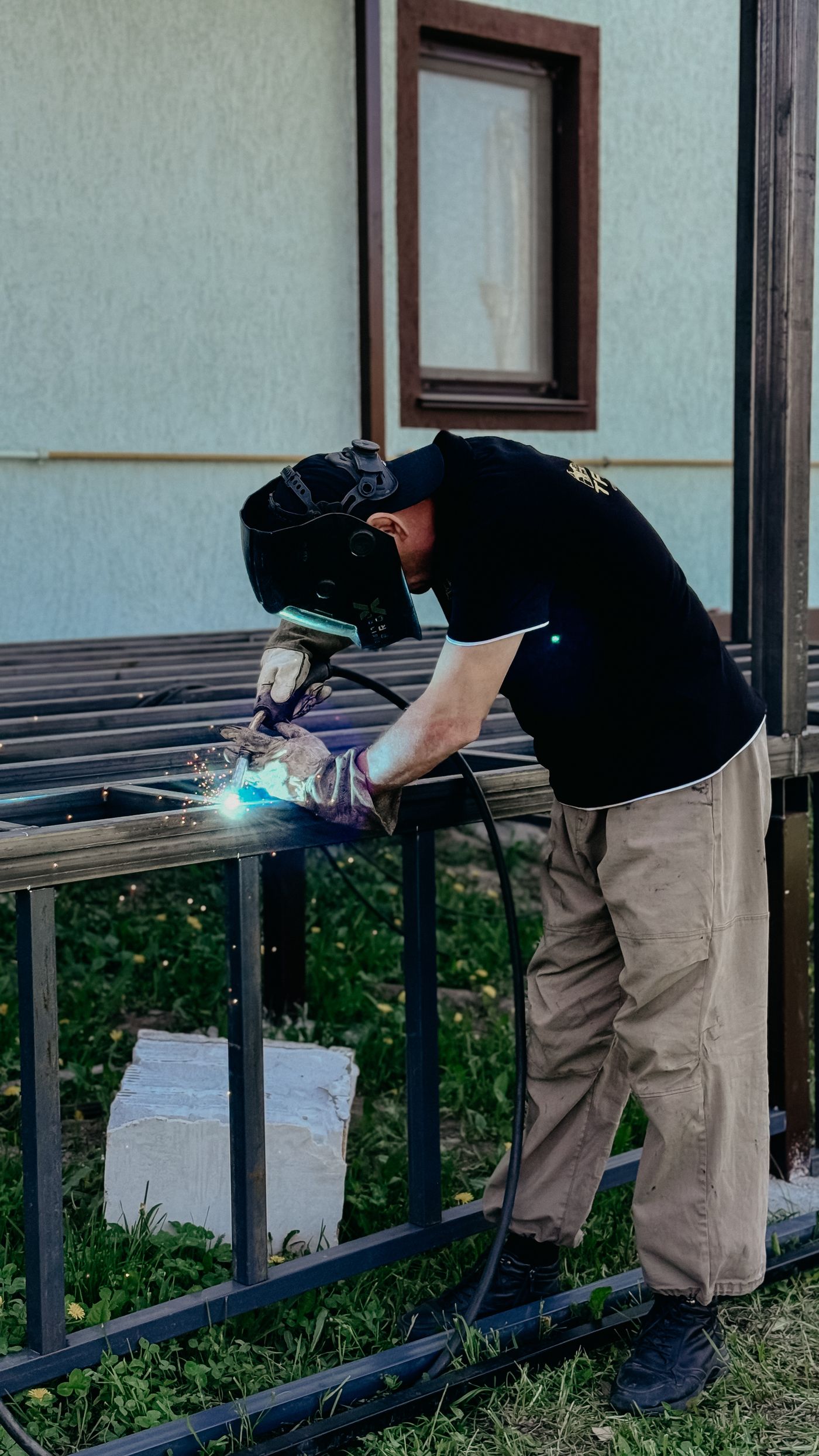 A skilled tradesperson welding steel framing outdoors, representing field crews and skilled trades.