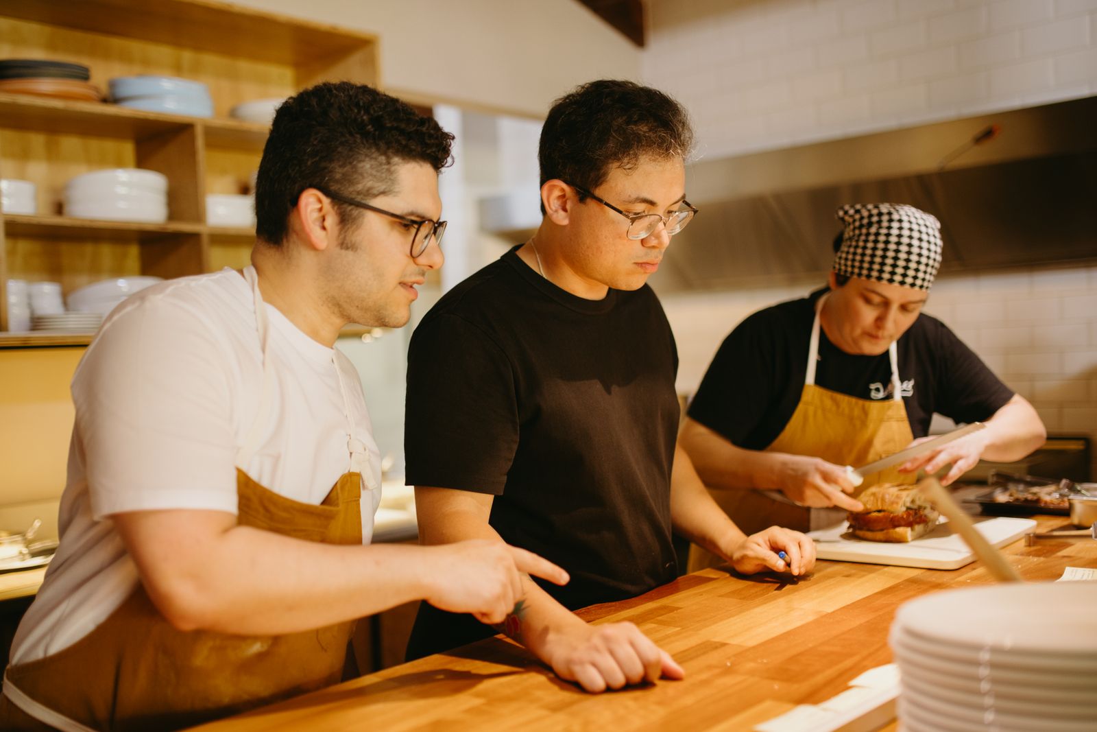 Back-of-house restaurant staff working side-by-side at a kitchen counter in a warm, collaborative moment.