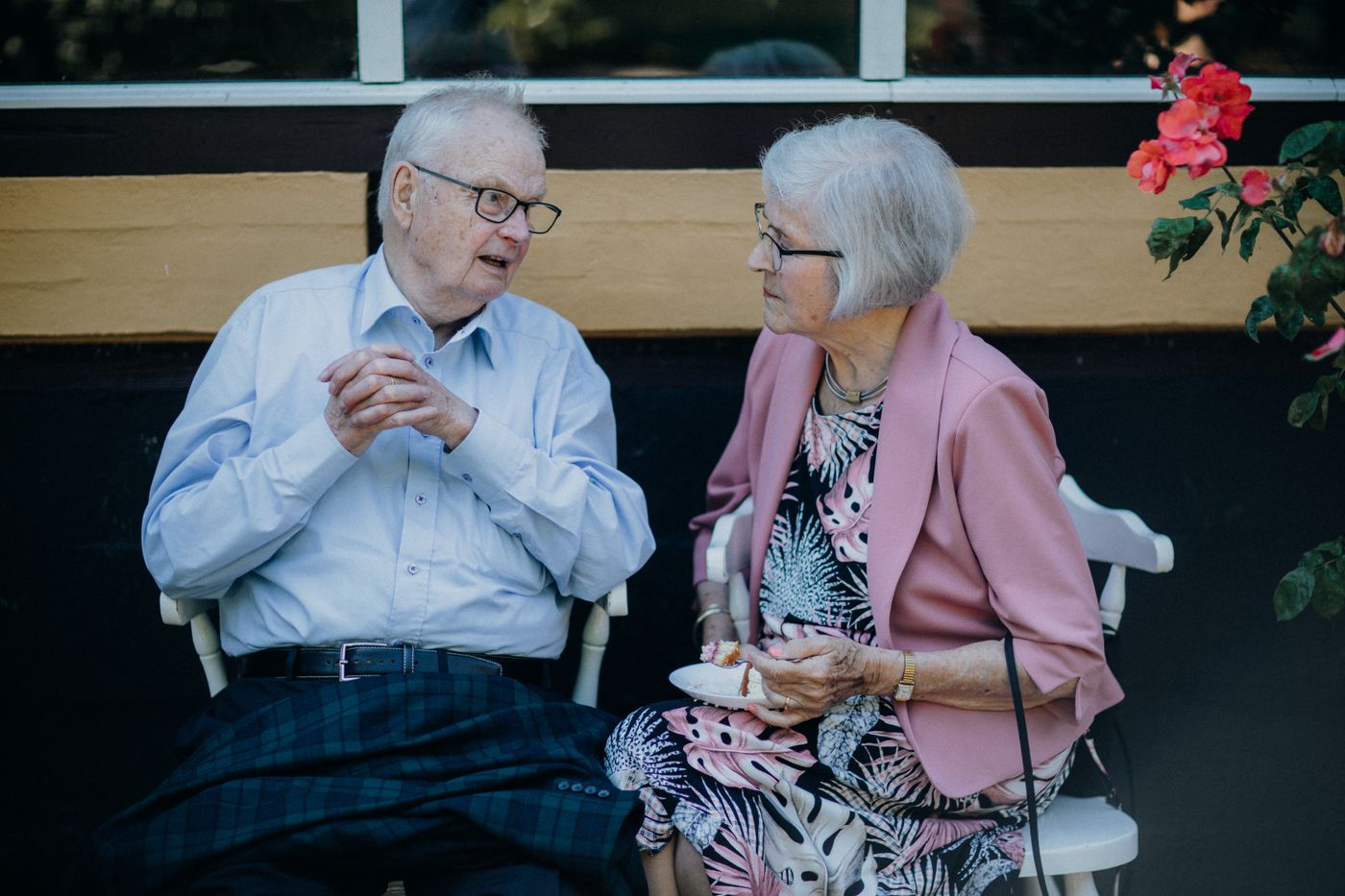 Two older adults seated together outdoors in a calm, dignified conversation.
