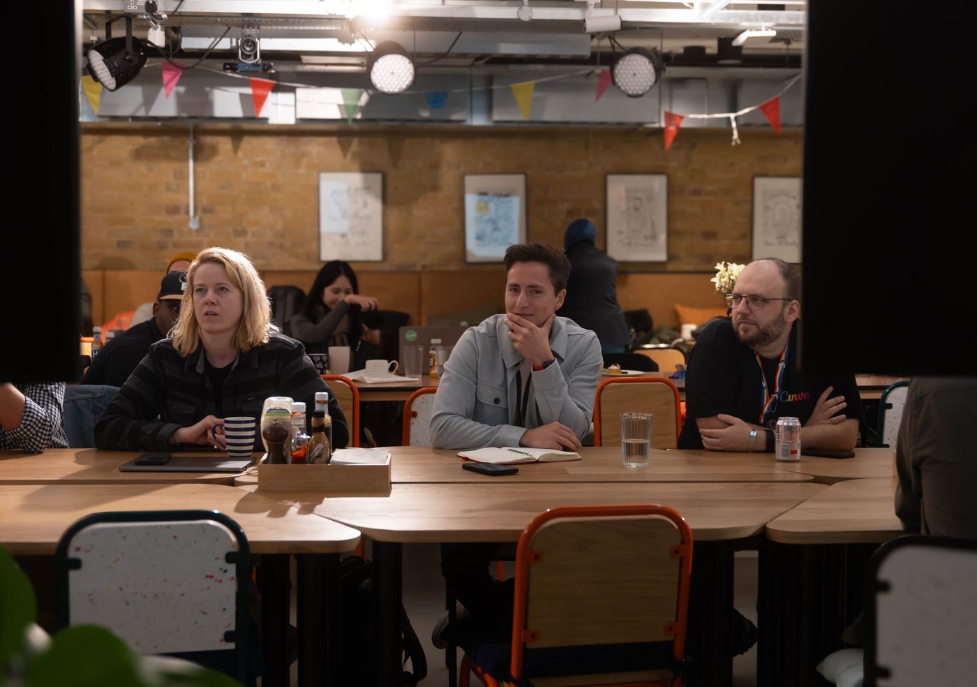 A small group of professionals seated around a warm, casual roundtable in an attentive, collaborative discussion.